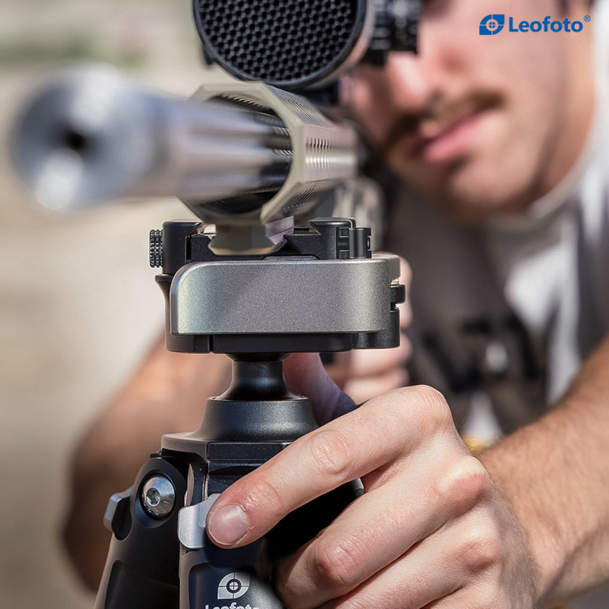 Hand adjusting a Leofoto SA-series leg-angle selector beneath a mounted rifle